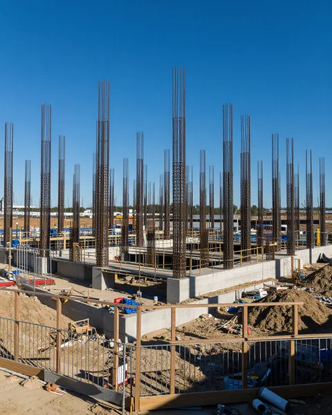 Rebar columns rising from poured concrete foundations on an active site
